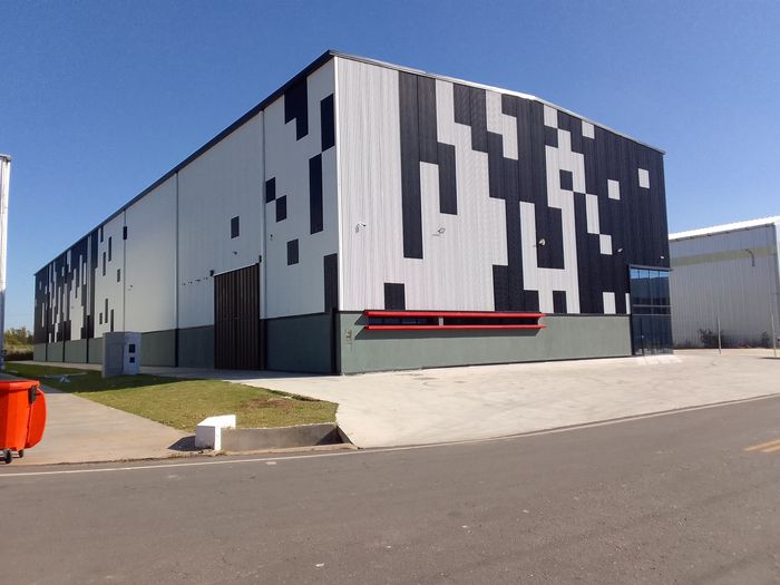 Nave industrial moderna con fachada de chapa color, obra reciente de Amione Construcciones